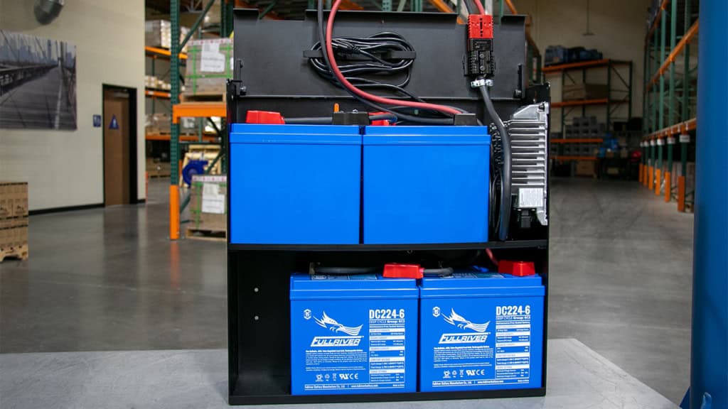 A battery pack with Fullriver Batteries placed in an warehouse setting with shelves and boxes in the background.