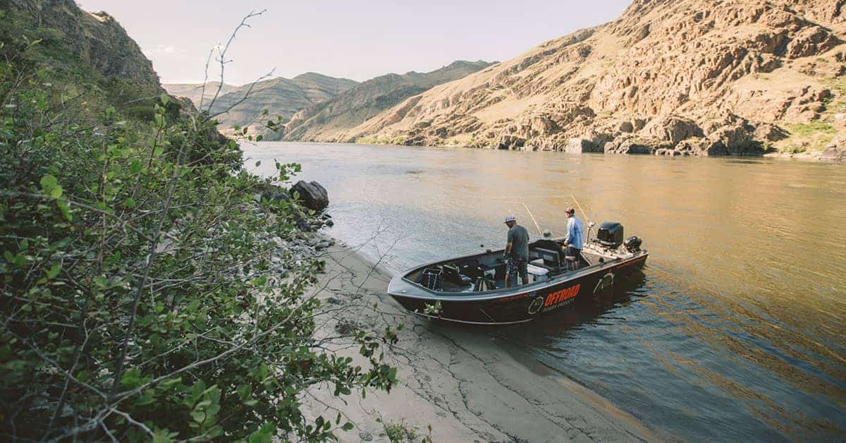 A group in a boat fishing on the lake shore.