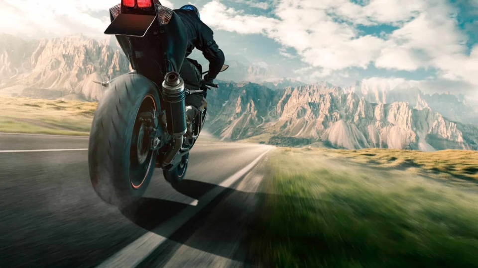 Rider on a motorcycle flying down the road towards the mountains