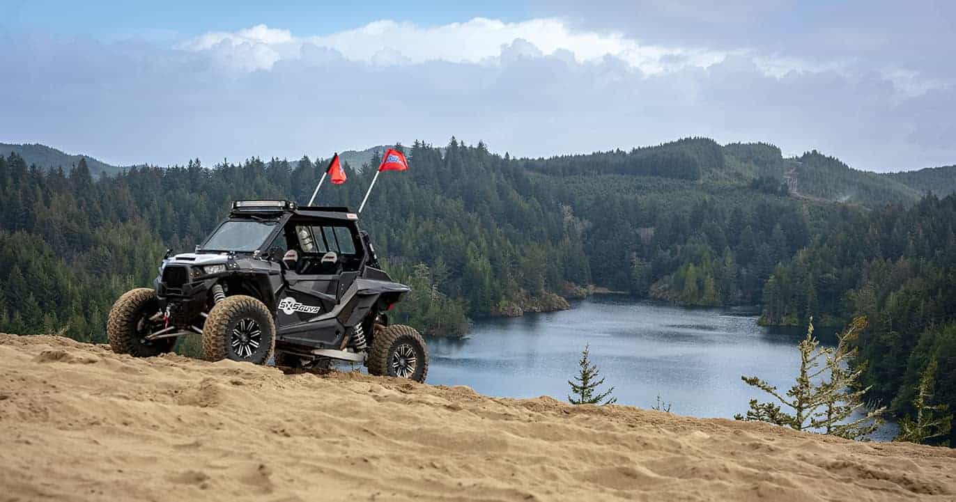 A UTV sits in front of a scenic lake surrounded by lush green trees in Winchester, Oregon.